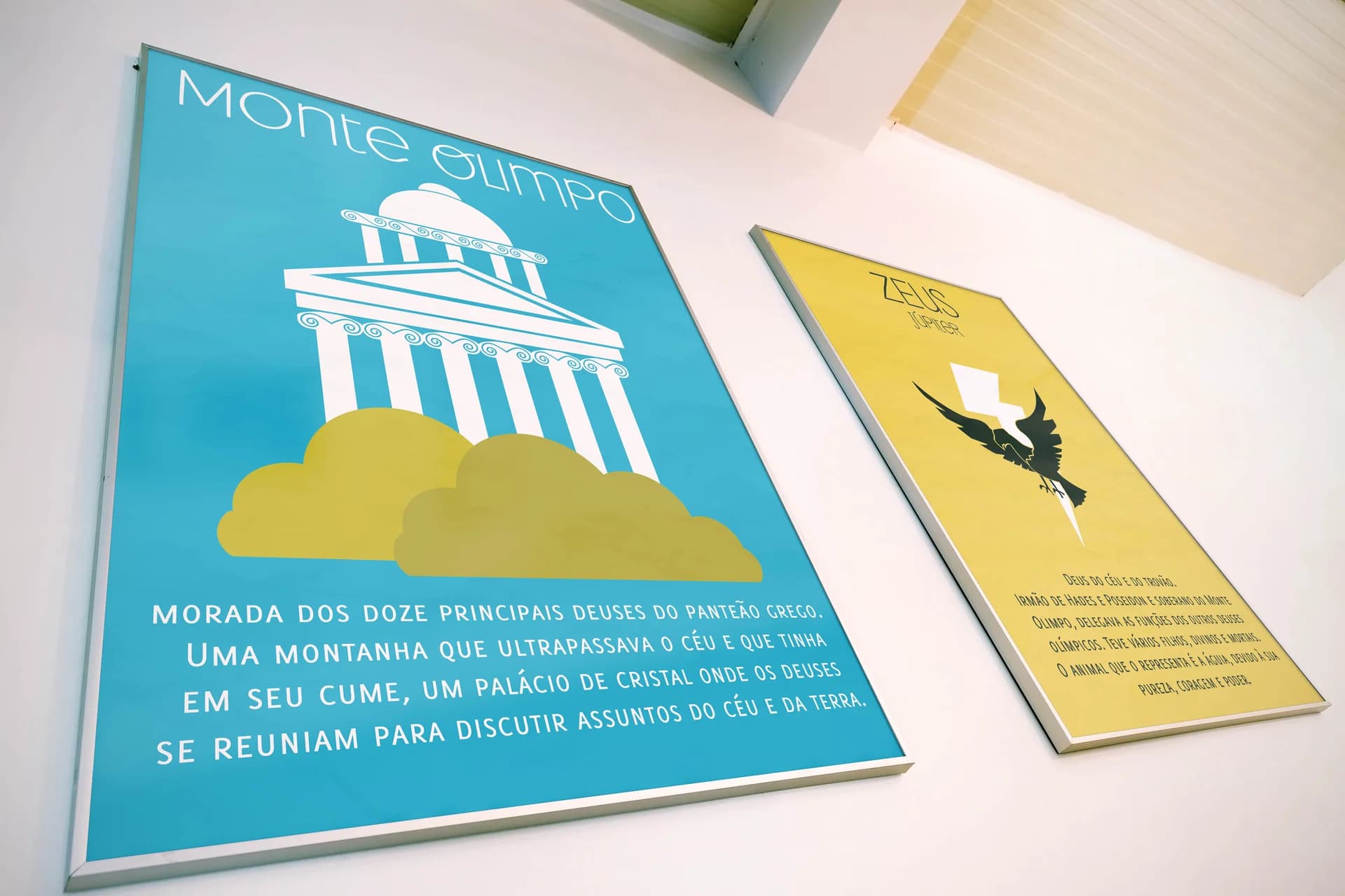 Framed Monte Olimpo and Zeus posters hanging side by side on a wall